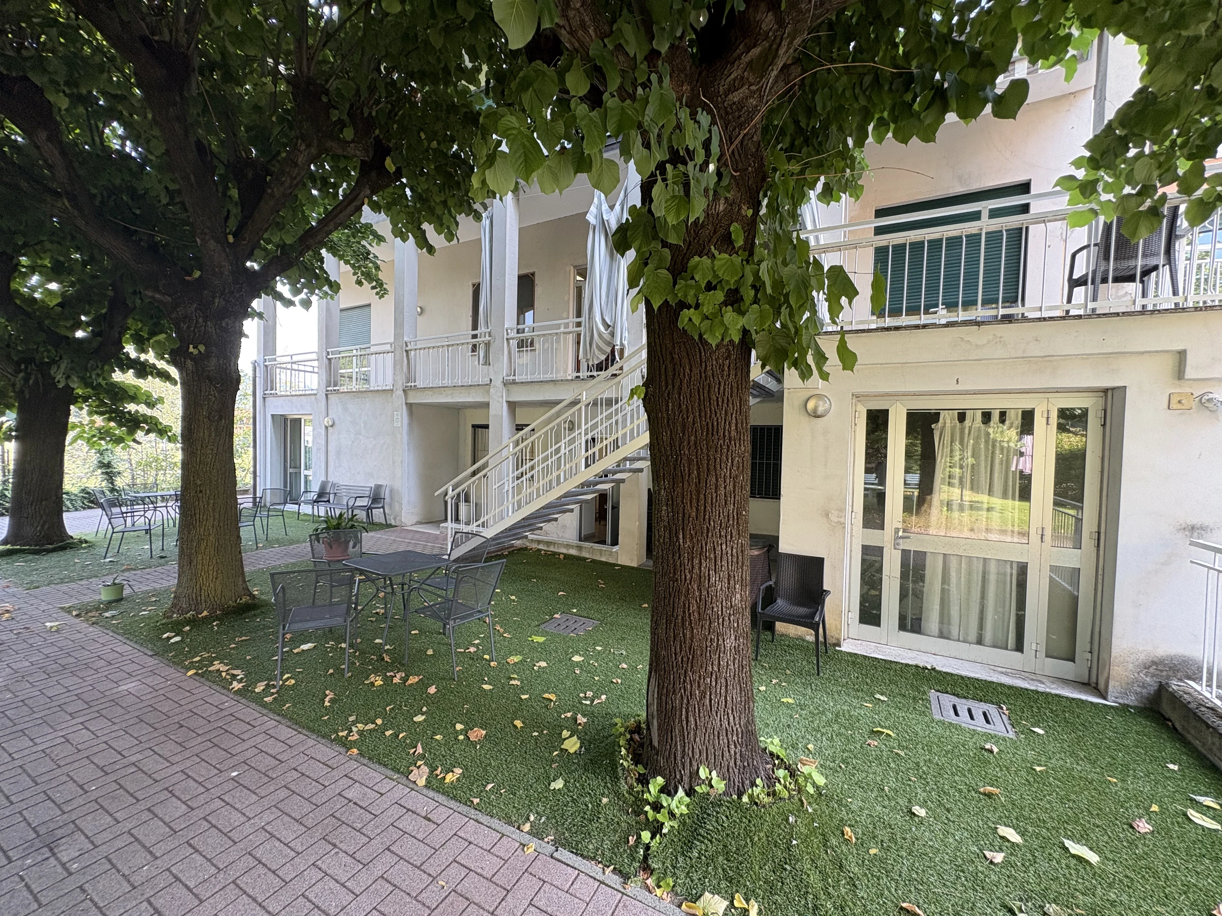 Cortile alberato con tavoli e sedute all’esterno