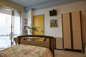 Camera della struttura arredata con letto, armadio e accesso alla luce naturale